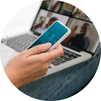 Image of a person holding a phone in hand next to a laptop.